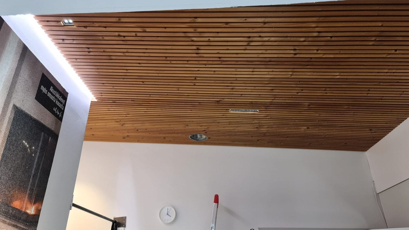 20210927_160153 - LedStore Puupaneloitu katto on varustettu upotetulla LED-valaistuksella ja pienellä ilmanvaihtoritilällä. Seinäkello ja osa takasta ovat näkyvissä, kun taas punakahvainen harja nojaa valkoista seinää vasten. Sopivaisia LED-valaisimet löydät helposti helposti LedStore.fi-verkkokaupasta!