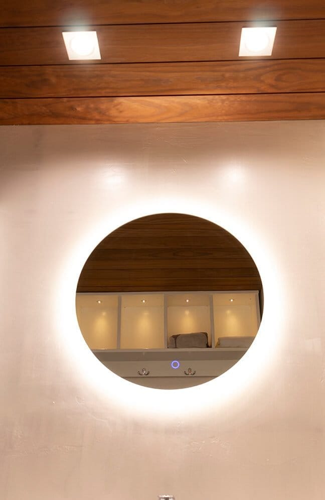 IMG_3018 - LedStore Pyöreä valaistu peili, jossa LED-valaistu hyllyt heijastuvat, puinen katto ja neliömäiset kattovalot luovat lämpimän ja kutsuvan tunnelman.