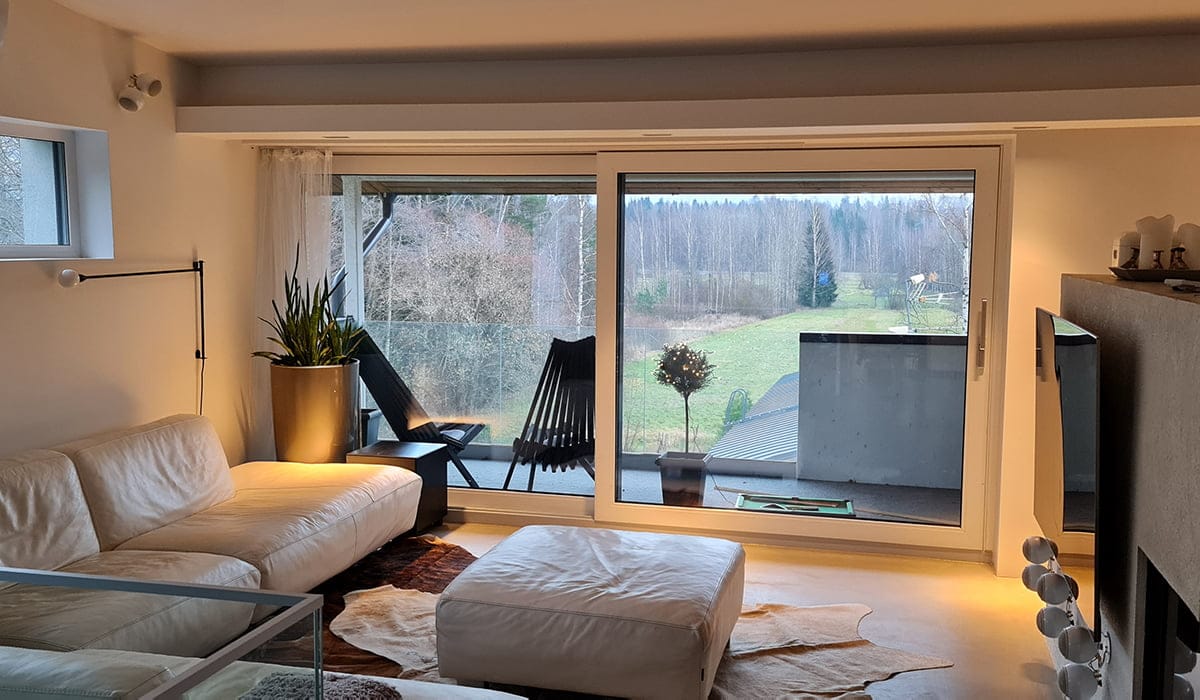 - LedStore Moderni olohuone, jossa on valkoiset nahkahuonekalut ja LED-valaistus, ja lasiliukuovet avautuvat parvekkeelle, jolta on näkymät nurmikolla.