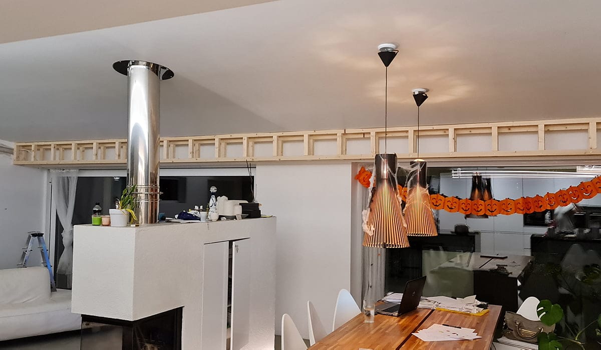 - LedStore Moderni olohuone, jossa kaksi LED-riippuvalaisinta puisen ruokapöydän päällä, halloween-seppele kurpitsoilla ja valkoinen takka vasemmalla.