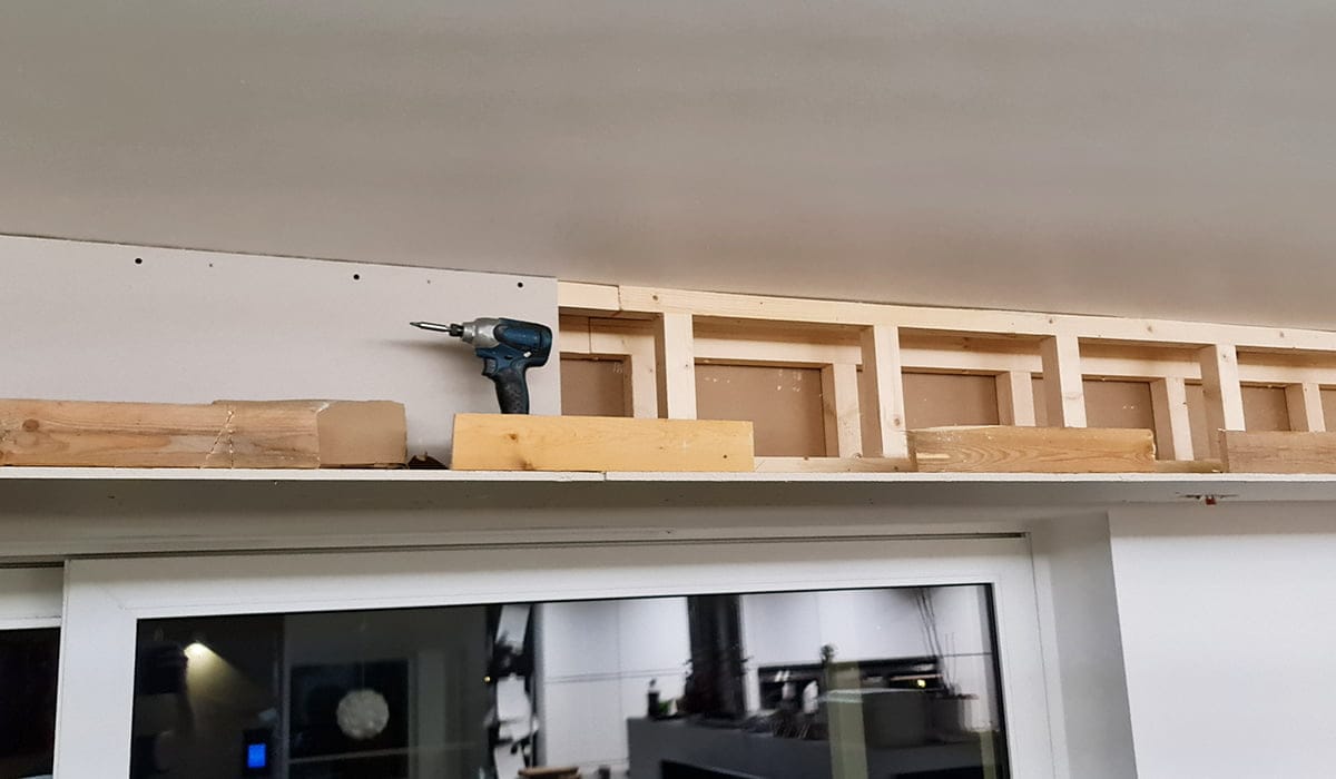 - LedStore LED-valaistu puinen runko ikkunan yläpuolella, sähköpora ja puu kielekkeellä; sisätila, jossa taustalla näkyy erilaisia laitteita.