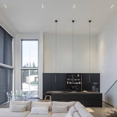 Modern köksbelysning med pendellampor, naturligt ljus från stora fönster, stämningsfulla och accentuerande LED-lampor.