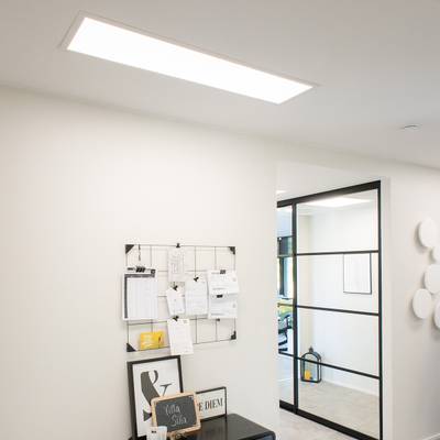 LED-takarmaturer för kontor belyser ett modernt arbetsutrymme med en glasvägg och en svart tavla.