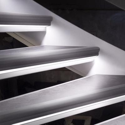 En detaljerad vy av en flytande trappa med en snygg LED-belysningsarmatur, accentbelysning och en vit vägg.