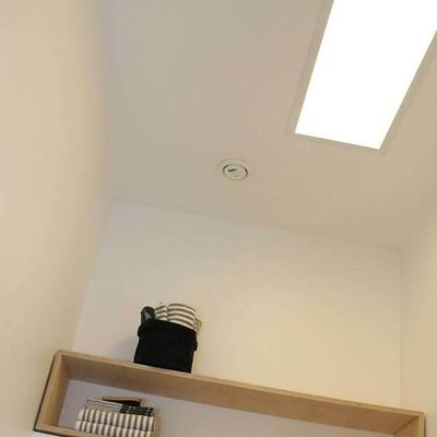 Mysigt rum med trähylla, randig filt, korg, böcker. En accentuerande LED-taklampa och brandvarnare för säkerhet och stil i ett modernt hem.