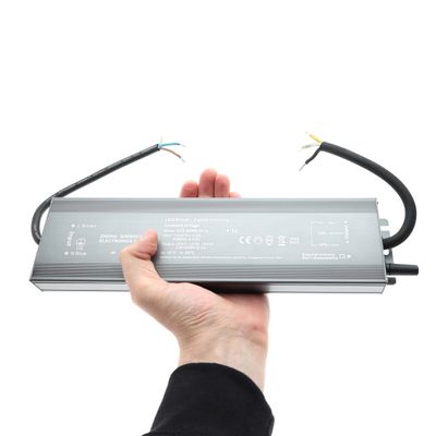 Rektangulär LED-kontroller med sladdar i handen, mot en vit bakgrund - energieffektiva belysningslösningar i vår LED-butik.