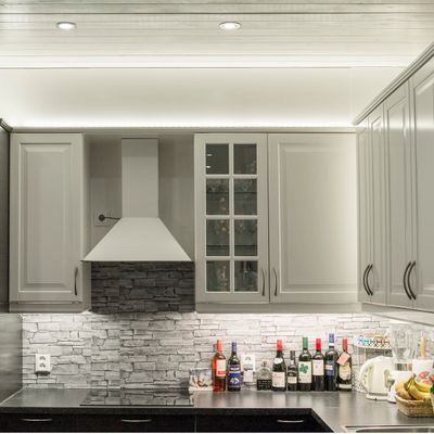 Kök med vita skåpluckor och LED-lampor ovanför och under de övre köksskåpen.