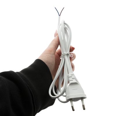 Närbild av en hand som håller i en tvinnad vit elkabel med en europeisk tvåpolig kontakt och synliga trådar, perfekt för anslutning av LED-belysning.