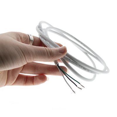 Närbild av en hand som håller i en vit LED-ringlampa med synliga kablar mot en mörk bakgrund för energieffektiv belysning.