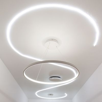 Spiralmönstret av moderna cirkulära LED-taklampor på ett vitt tak förstärker modern ljusdesign.