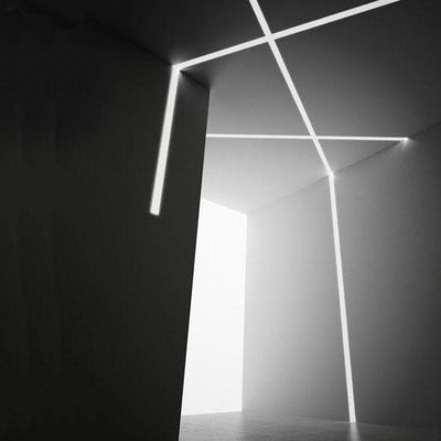 Ett mörkt minimalistiskt rum upplyst av korsande vita LED-linjer på väggarna och i taket, som bildar ett abstrakt geometriskt ljusmönster.