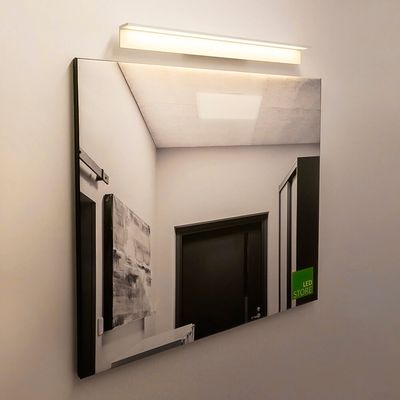 Alternativ text: En modern hall med vita väggar, en mörk dörr och en LED-armatur som reflekterar från spegeln skapar en modern LED-belysning.