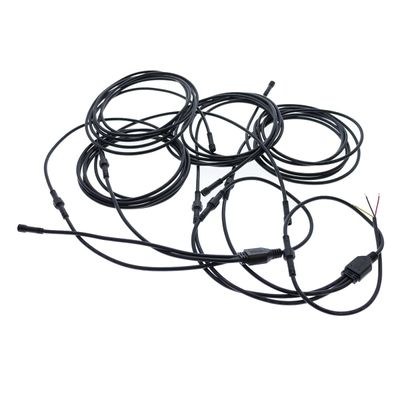 Långa LED-fiberoptiska kablar med kontakter och nakna trådar, på vit bakgrund, tvinnade för armaturer.