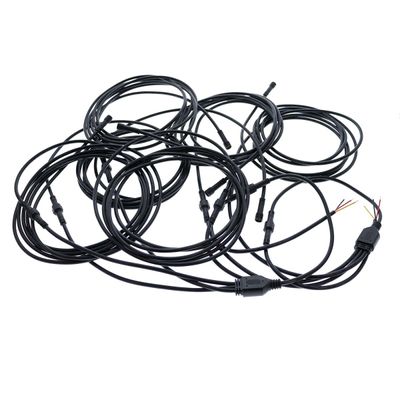 Svarta LED-fiberoptiska kablar med kontakter och synliga trådar, lindade och trassliga mot en vit bakgrund.