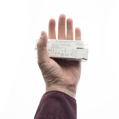 Alternativ text: hand som håller en vit LED-belysningskontroll med symboler mot en klar bakgrund, vilket belyser den tekniska innovationen hos LED-belysningslösningar.