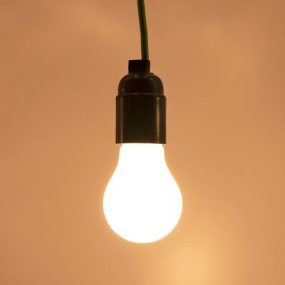 LED-lampa med grön tråd som lyser varmt mot en brun bakgrund. Idealisk för energieffektiva belysningslösningar och för att förhöja stämningen.