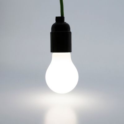 LED-lampa hängande på en grön tråd som lyser upp en vanlig bakgrund. Perfekt för energieffektiva belysningslösningar.