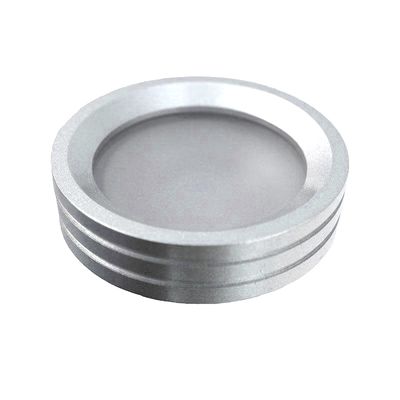 Rund silverfärgad LED-armatur med räfflade kanter, snedställd, vit bakgrund. Idealisk för moderna belysningslösningar och för att förstärka rumsinredningen.