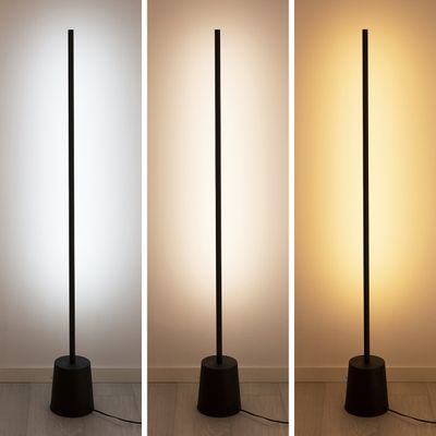En hög svart golvlampa erbjuder mjukt vitt, ljusvitt och varmt gult mot en neutral vägg och framhäver mångsidig LED-belysning.