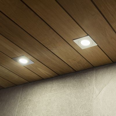 Alternative text: 'Trätak med infällda LED-lampor som lyser upp en strukturerad grå vägg i en modern belysningsbutik