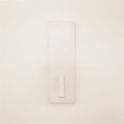 Minimalistisk vit väggskulptur med rektangulär bas och centralt cylindriskt utsprång, upplyst av LED-belysning för att öka designens attraktionskraft.