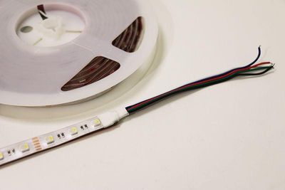 LED-lampor med röda, gröna och svarta trådar på en vit yta för heminredning, skåpbelysning, energieffektiva lösningar.