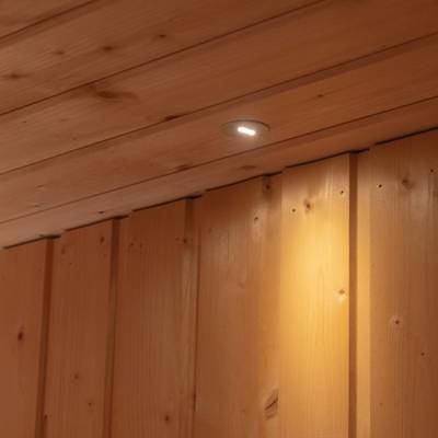 En takmonterad LED-armatur belyser väggpanelerna av trä nedanför.