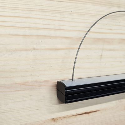 Pendellampa i svart metall med metallram mot en ljus trävägg i en LED-belysningsbutik.