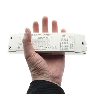 I handen, en vit rektangulär enhet med teknisk information och symboler samt ordet "Zigbee" som förknippas med LED-belysningsteknik.