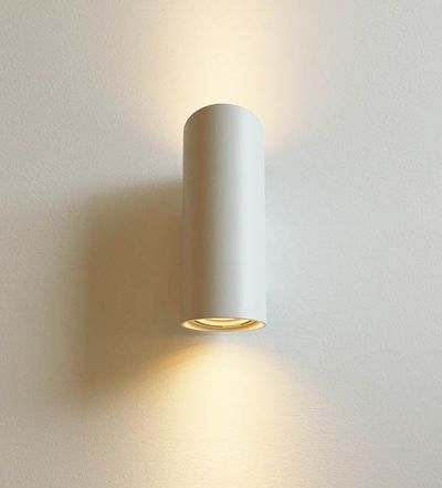 En elegant cylindrisk LED-vägglampa som ger en varm ljusstråle upp och ner på en vit vägg; perfekt för moderna, minimalistiska interiörer.
