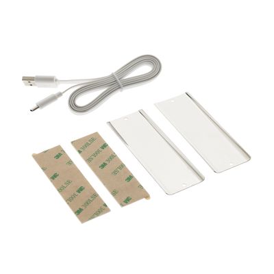 Installationssats för LED-belysning: USB-kabel, självhäftande remsor och rektangulära vita plastdelar med vit bakgrund.