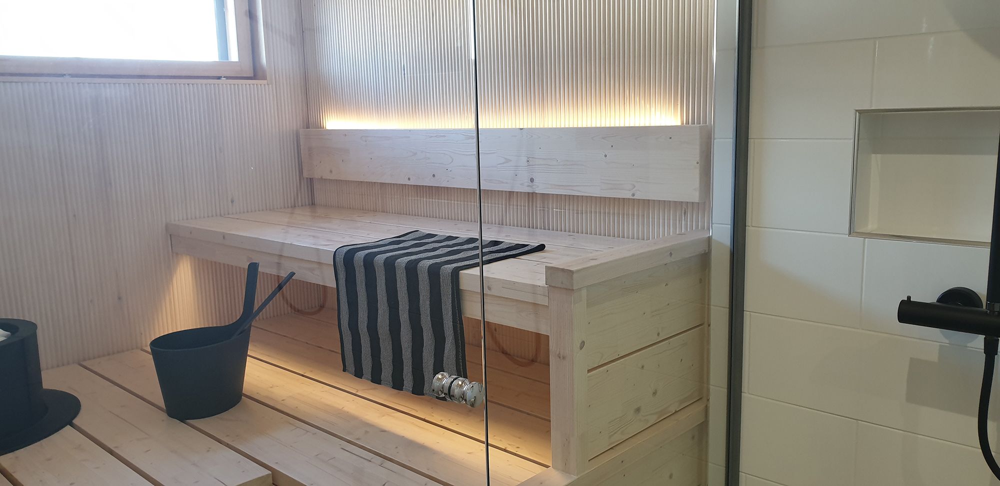 LED-list på baksidan av bastuns ryggstöd ger stämningsfullt ljus uppåt och nedåt under taket. Ledstore.fi