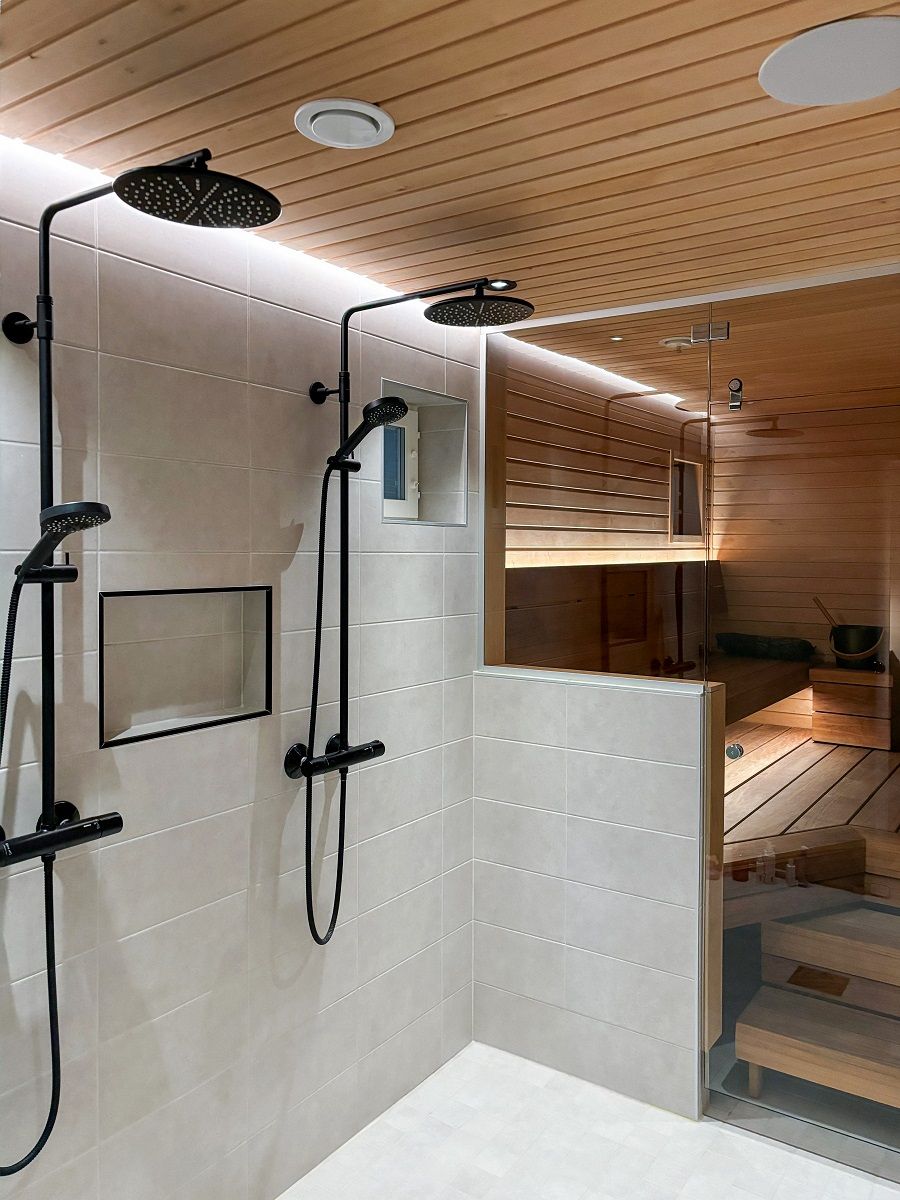 Bakom duscharna sitter en LED-list i ett spår i taklinjen som indirekt lyser upp längs väggen ner till golvet. Ljuset är både effektivt och ögonvänligt. © LedStore.fi