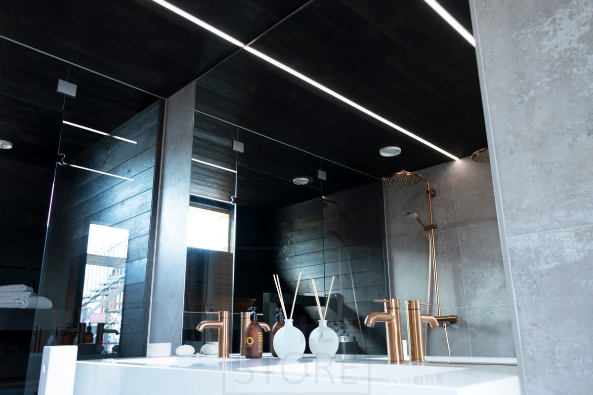 Bostadsmässa 2020: LED-lister som belyser badrummet i smala infällda profiler i det svarta taket i tvättrummet. Ledstore.fi