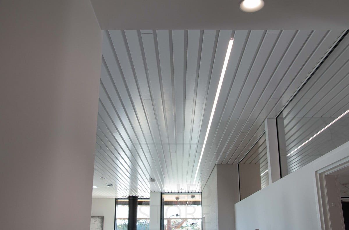 Housing Fair 2022: Vit led-profil inbäddad i fogen på en takpanel i vardagsrummet. Ledstore.fi