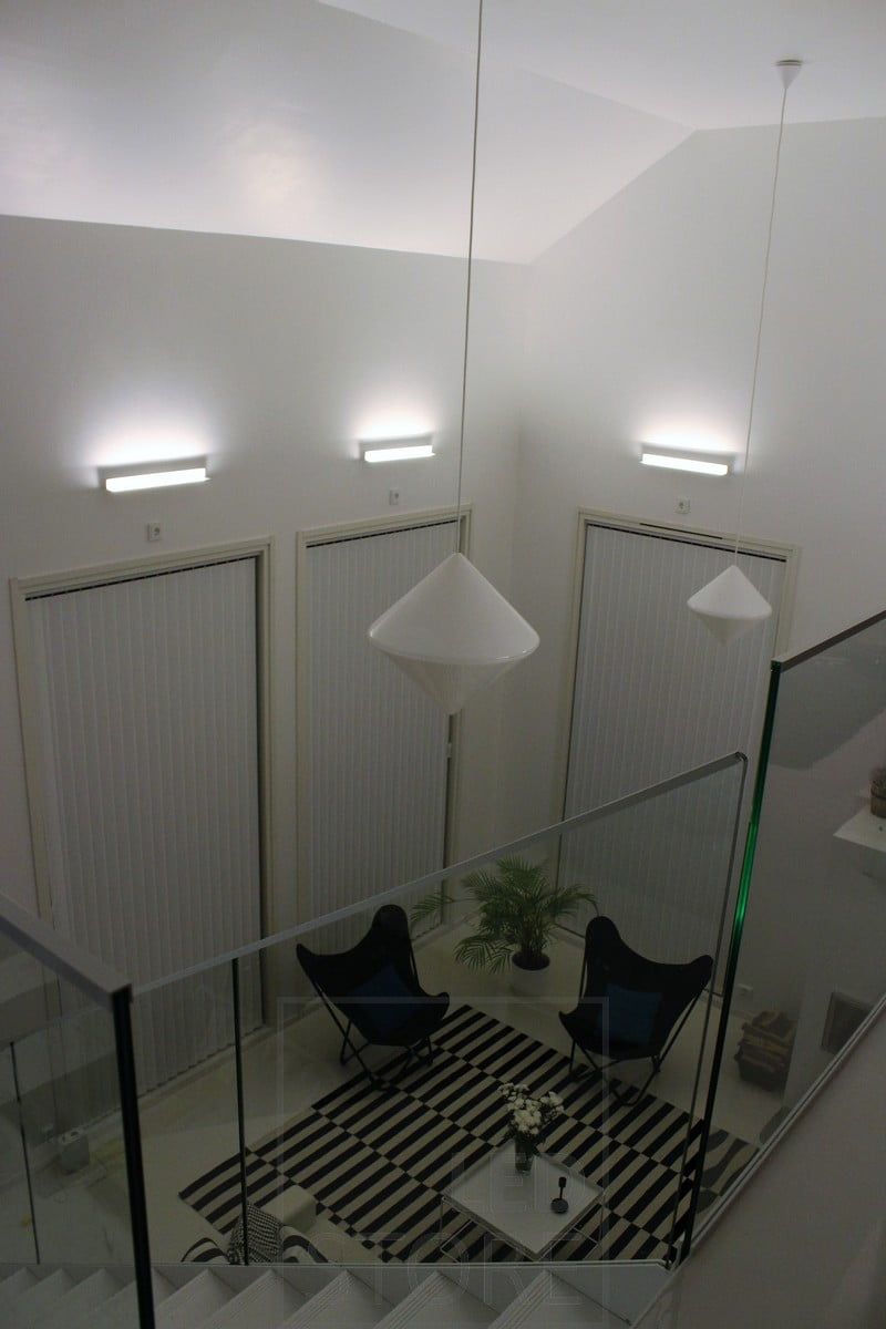 Ett vardagsrum med stämningsfull indirekt belysning skapad med Led BLADE vägglampor. Armaturen är monterad så att den lyser nerifrån och upp, vilket gör att den indirekta belysningen också framhäver rummets höjd. Ledstore.fi