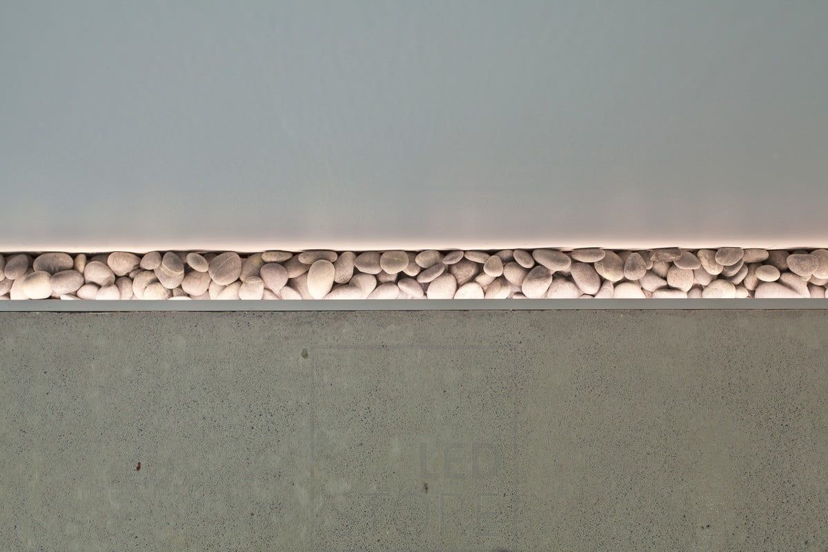 Vacker detalj på golvet som framhävs av en led-remsa. När golvet gjöts lämnades en liten fördjupning bredvid väggen för att lägga till stenar och stämningsbelysning installerades för att framhäva stenarna. Fungerar även som ett stämningsfullt nattljus. Ledstore.fi