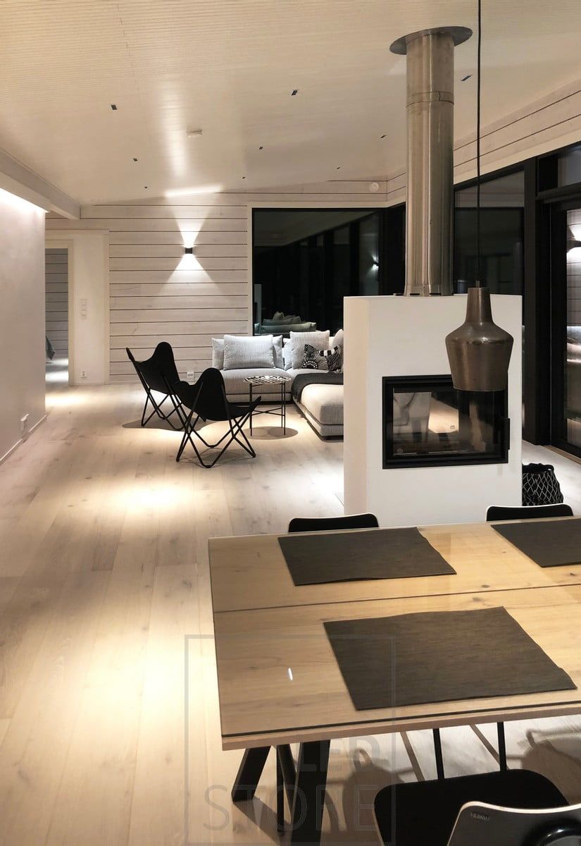 Den svarta vägglampan FUNK belyser vardagsrummet med stämningsfullt ljus genom väggen. Som allmänbelysning i rummet lyser LINJA 2 spotlights upp det nischliknande ljuset. Ledstore.fi