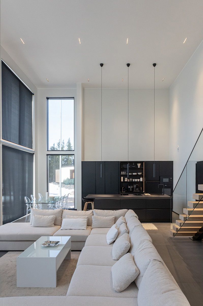 LINJA10 strålkastare för allmänbelysning i taket i vardagsrummet, köket och matplatsen samt tre LED PIIPPU 2.0 pendellampor ovanför köksön.