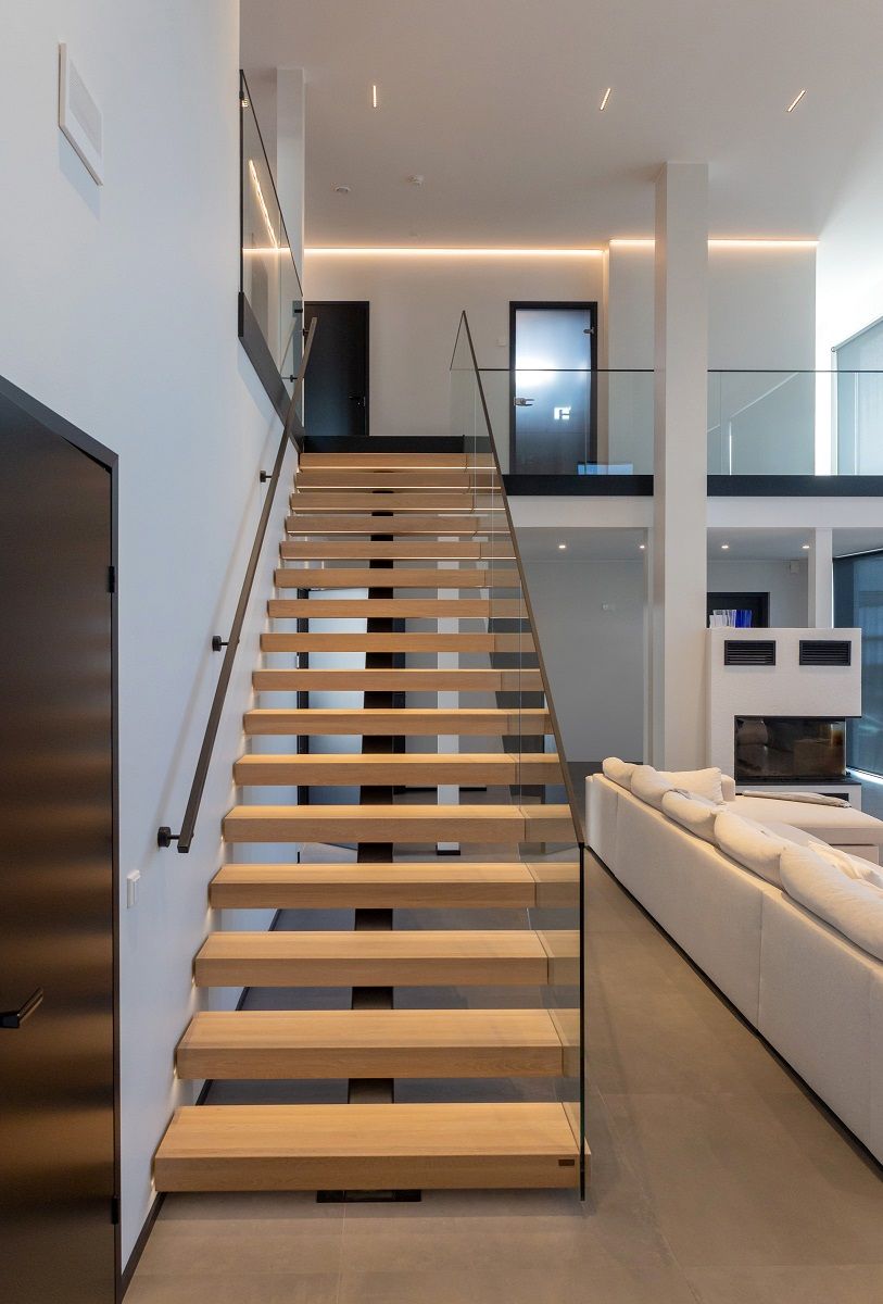 Ljus trätrappa som leder upp till övervåningen upplyst av en led-list och en led-list som löper runt väggen på övervåningen