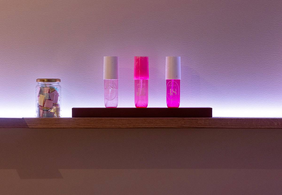 En färgjusterbar LED-remsa monterad bakom hyllan ger ett lila ljussken på väggen.