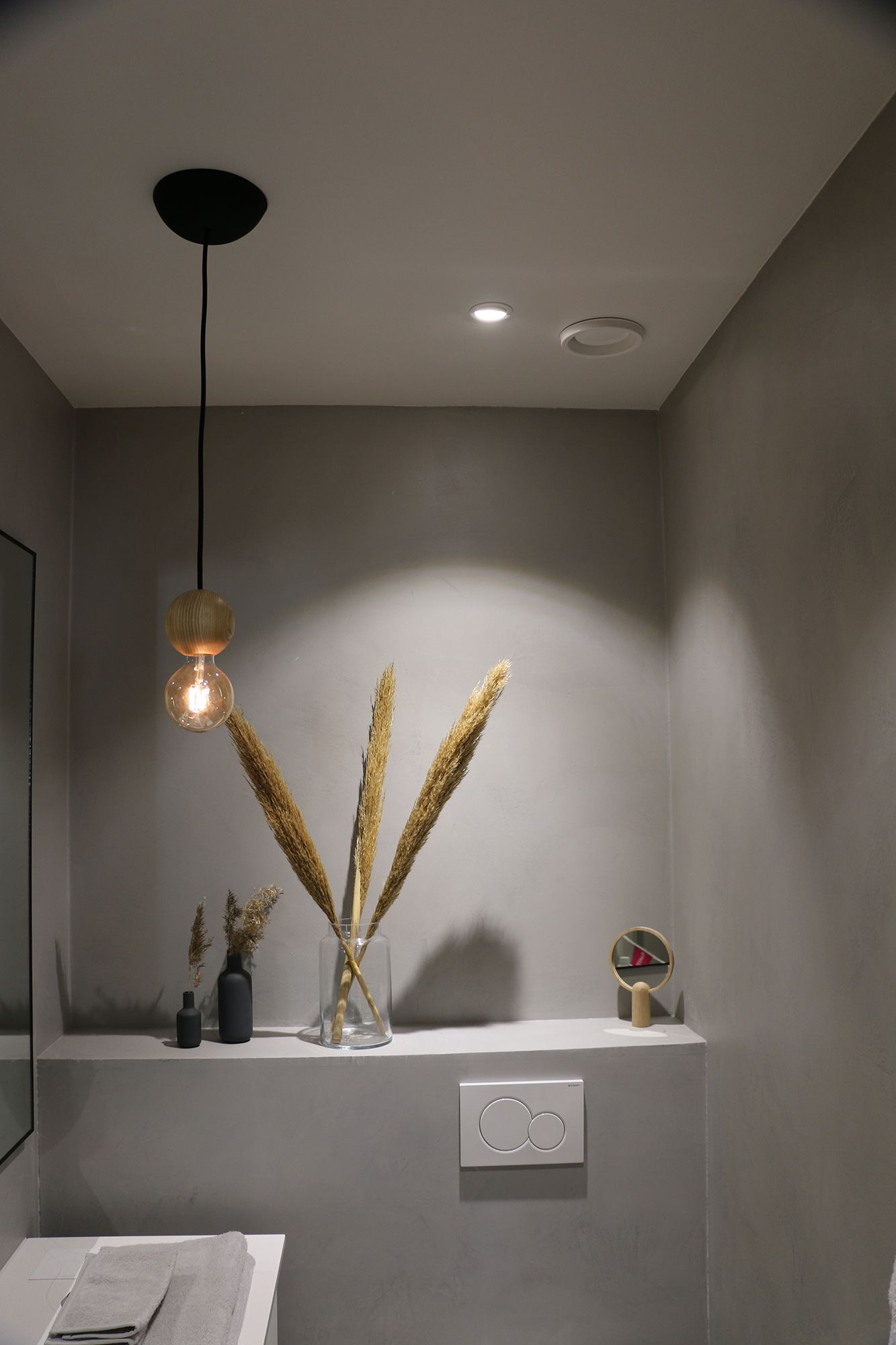 Spotlight som belyser föremålen på hyllan och själva hyllan. Spotlighten nära väggen framhäver även lampans ljusmönster. Ledstore.fi