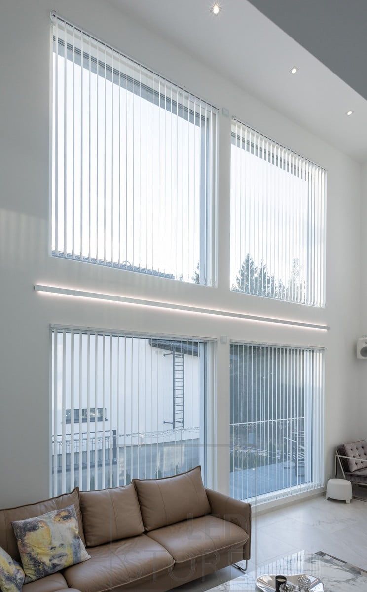 LED-lister i en dubbelriktad väggprofil för att framhäva höjden på vardagsrummet och fönstren. Profil och LED-lister kan måttbeställas enligt dina egna mått. Cirkulära led-spots i taket för allmänbelysning. Ledstore.fi