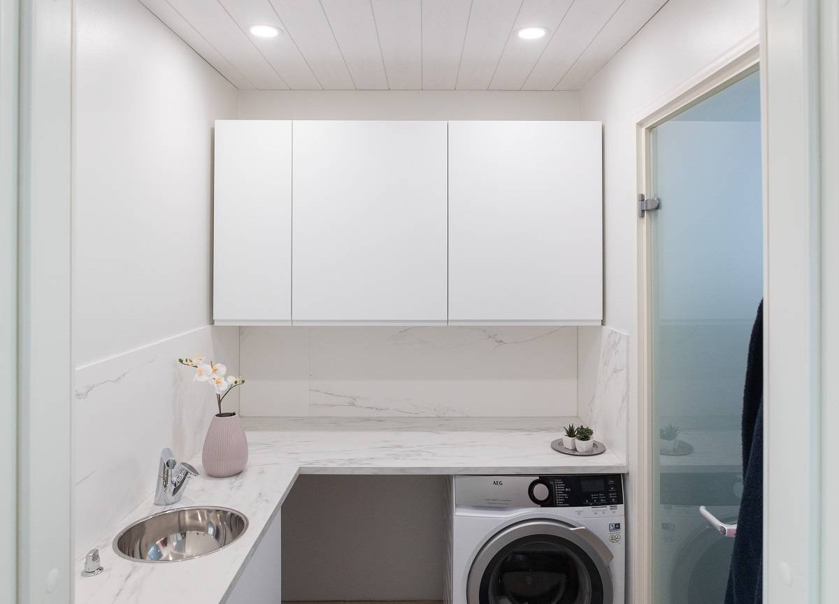 Små runda panellampor infällda i taket i en tvättstuga.