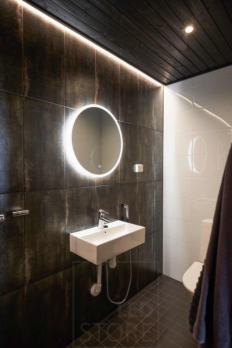Mörkt badrum med stämningsfull belysning med spotlights och indirekt ljus. Den ljusa spegeln har en avimningsfunktion som gör att spegeln förblir ljus när man kommer ut från bastun eller duschen. Ledstore.fi