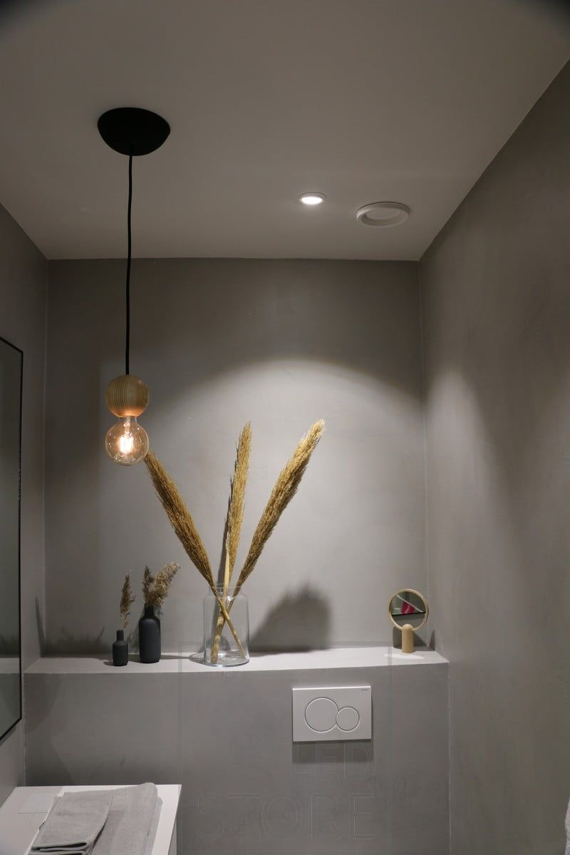 Spotlight som belyser föremålen på hyllan och själva hyllan. Spotlighten nära väggen framhäver även lampans ljusmönster. Ledstore.fi