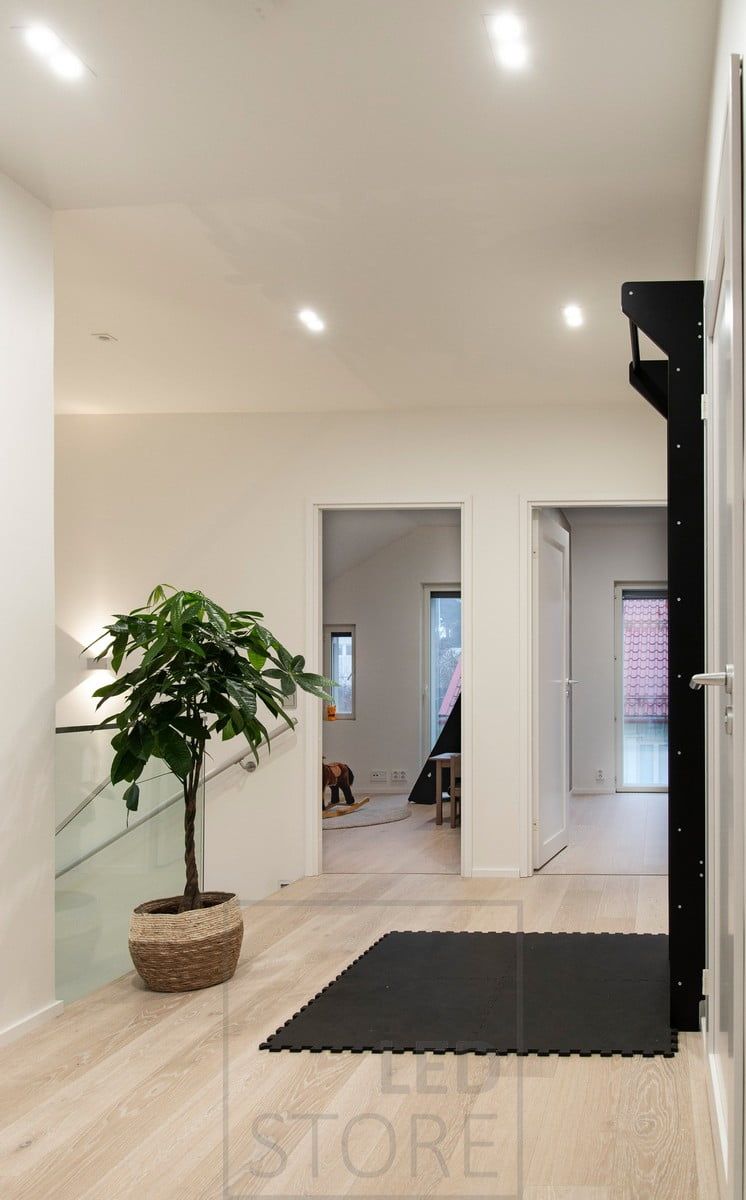 Allmänbelysning med TUPLAKANTTI led-spots i taket och en dubbelriktad vägglampa på väggen för att skapa ett stämningsfullt ljus i trapphuset. Ledstore.fi