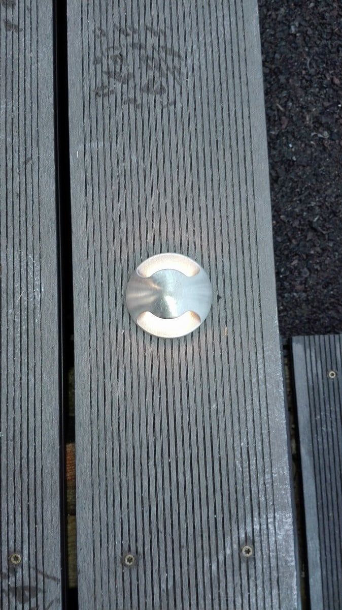 En terrasskruka som är infälld i trädäcket. Ljuset lyser i två riktningar genom terrassen. Ledstore.fi