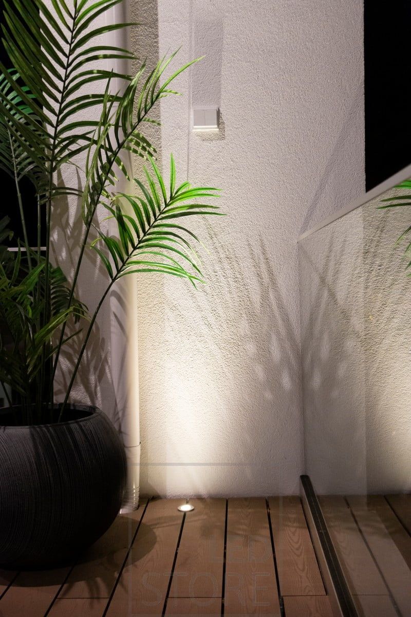 En uppåtriktad spotlight inbäddad i terrassen använder väggen som en reflekterande yta för att kasta ett atmosfäriskt ljus från botten och upp. Ledstore.fi