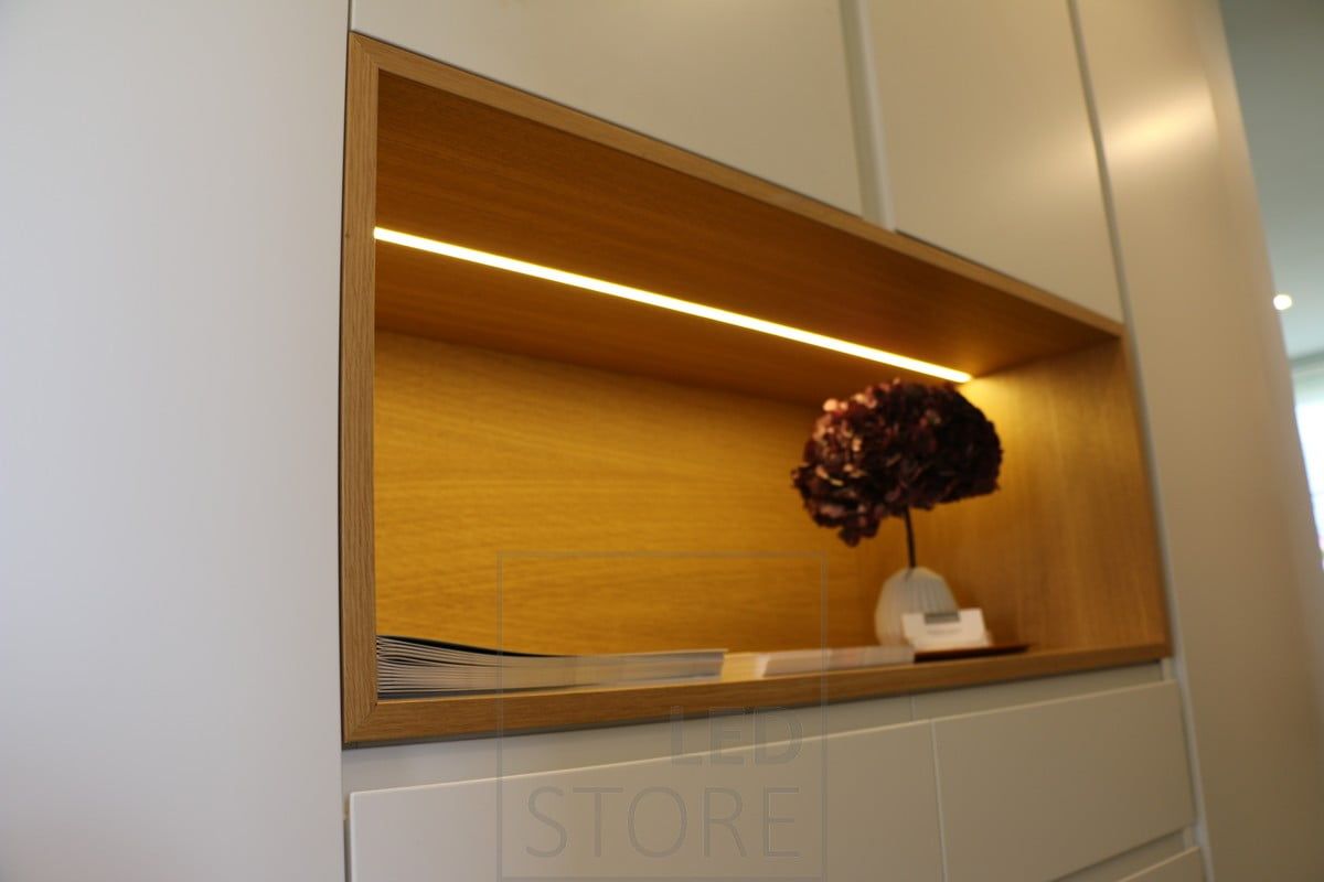 LED-ljusramp monterad på hyllan i ett skåp i en infälld profil. Belysningen är stämningsfull och lyfter fram en vacker detalj. Ledstore.fi
